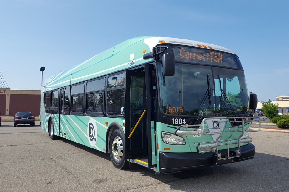 An image of a new DDOT bus outside. It has a light green wrap with bright rays emanating from the back of the bus